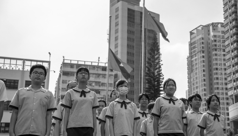 Des élèves se tiennent devant le drapeau après la cérémonie de lever du drapeau le 30 septembre 2023 à Hong Kong, Chine.