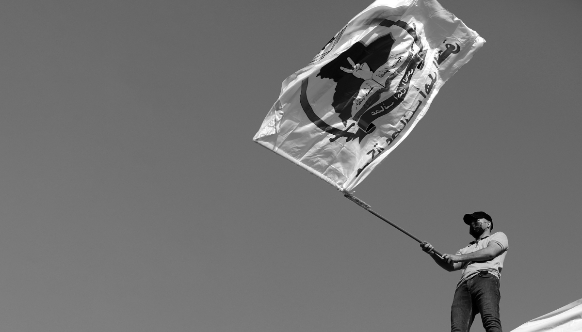 Un partisan du groupe militant Asaïb Ahl al-Haq, ou Ligue des vertueux, porte son drapeau lors d'une manifestation près de l'entrée de la zone verte dans le centre de Bagdad, en Irak, le 14 juillet 2023. 