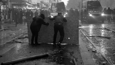Paris, octobre 2026 : des manifestants se mettant à l'abri  font face à des gendarmes. 