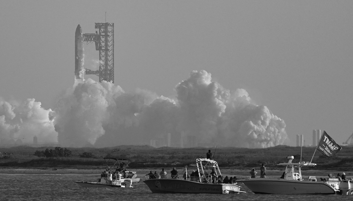 Un drapeau de Trump sur un bateau, alors que des personnes regardent le Starship de SpaceX décoller de la base Starbase près de Boca Chica, au Texas, le 6 mars 2025.