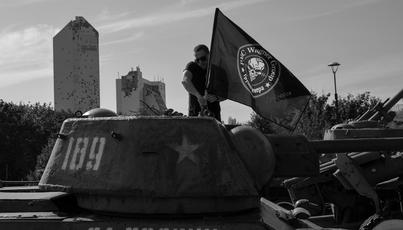 Un homme attache un drapeau Wagner à un char d'assaut à Donetsk, en Ukraine contrôlée par la Russie, le 1er octobre 2023.